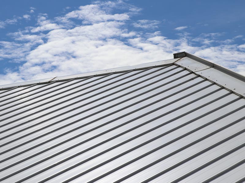 Close up of light gray metal roof panels at roof peak