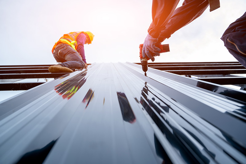 Two workers installing a metal roof panel